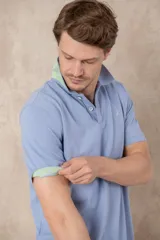 Chomba azul con cuello clásico, tapeta de dos botones y logo bordado en el pecho.