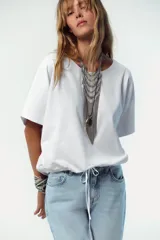 Camiseta blanca de algodón con cuello redondo, mangas cortas y bajo asimétrico ajustable con lazadas.
