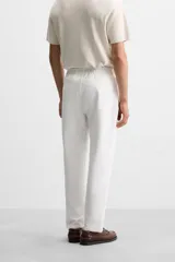 Pantalón de jogging color beige confeccionado en tejido de mezcla de algodón. Cuenta con cintura elástica ajustable con cordón, bolsillos frontales y traseros.