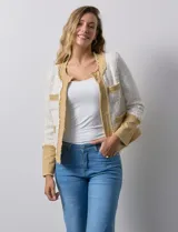 Chaqueta Nanette en tejido tweed color crudo con detalles en denim azul. Tiene cuello a la base, abertura central, bolsillos delanteros, puños con aplique de botones perlados, terminación desflecada y forro interno.
