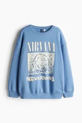 Buzo celeste de algodón con cuello redondo y mangas largas. Estampado frontal con el logo de la banda Nirvana y la imagen de la portada del álbum Nevermind.