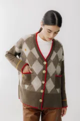 Cárdigan color beige con patrón de rombos en tonos marrones, cierre con botones, bolsillos frontales y bordados de cerezas.