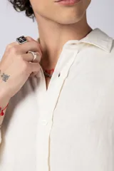 Camisa color arena de lino, manga larga, con cuello clásico y corte holgado.