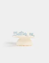 Broche para el pelo color crema, con forma de pinza y apliques de flores celestes.