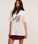 Remera blanca de algodón BCI con cuello redondo y mangas cortas. Presenta un bordado de un chihuahua con un suéter a rayas y la palabra "Hello".
