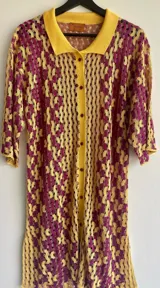 Vestido tejido con textura ondulada, cuello camisero y tajo lateral. Diseño a crochet en amarillo y fucsia.