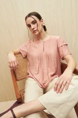 Blusa color salmón de tela liviana con volados en las mangas y botón de nácar.