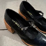 Zapato de cuero vacuno negro con punta cuadrada, tira con hebilla y taco de madera de 6cm.