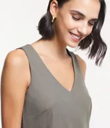 Musculosa verde oliva de piquet con escote en pico, breteles anchos, pequeñas aberturas laterales y bajos con pespuntes.
