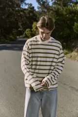 Buzo de manga larga color crudo con rayas horizontales color verde oliva, de corte oversize cropped y cuello redondo.