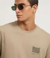 Remera color arena de algodón peruano, de corte recto, cuello redondo y manga corta. Presenta un pequeño estampado en el pecho.