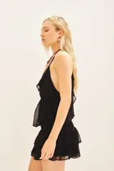 Top negro con escote en V y volados en el borde del escote. Posee tirantes finos ajustables y elástico en la cintura para un calce ceñido.