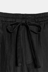 Pantalón negro de tiro medio con bolsillos delanteros y traseros. Cintura elástica ajustable con cordones.