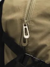 Mochila gris claro y gris oscuro con cordones elásticos cruzados en el frente y logo de la marca en la parte superior.