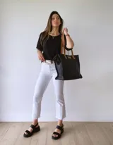 Bolso tipo tote bag de cuero negro con forro de tela, doble asa de cuero color suela, bolsillo frontal y bolsillo interno.