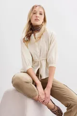 Camisa cruda de algodón jacquard con bordados a tono en el frente y las mangas. Tiene corte a la cintura con lazo interno ajustable, botones frontales y mangas largas con elástico en los puños.
