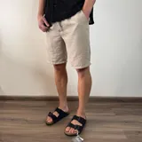 Bermuda color beige de lino con cordón ajustable en la cintura y bolsillos laterales.