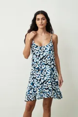 Vestido corto blanco de tirantes finos, con escote redondo y corte holgado tipo camisola, con un pequeño volante en el ruedo.