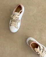 Zapatillas deportivas urbanas con capellada negra, detalles en beige y suela blanca.