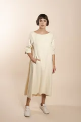 Vestido largo debajo de la rodilla, acampanado, color marrón, con cuello bote, bolsillos laterales y mangas 3/4 con detalle de tajo.