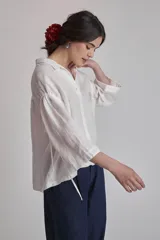Camisa blanca de lino con cuello clásico, cierre frontal con botones y mangas 3/4 abullonadas.