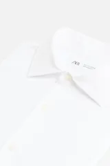 Camisa blanca de algodón, corte regular, con cuello italiano abierto, manga larga con puños abotonados y cierre frontal con botones.