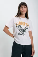 Remera color crudo de corte recto con estampado de un águila y la palabra 'Liberty' en color amarillo.