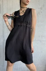 Vestido corto negro con escote en V, breteles finos y detalle de encaje en el busto.