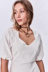 Vestido corto color beige de lino, con escote cuadrado, mangas cortas abullonadas y corte a la cintura.