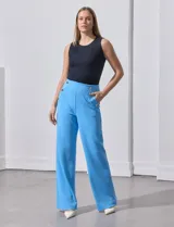 Pantalón largo de crepe elastizado color verde, de corte recto, con bolsillos delanteros y apliques de botones metálicos.