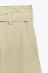 Pantalón cargo color beige de tiro alto con trabillas, bolsillos laterales y de vivo en espalda y pierna. Incluye cinturón lazada en el mismo tejido.