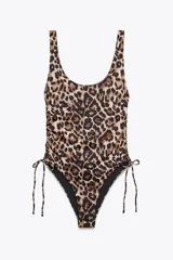 Bañador enterizo con estampado animal print, copas extraíbles, escote redondo y tirantes. Detalle de frunces ajustables con lazadas en los laterales y forro interior.