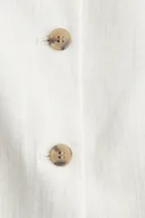 Chaleco sastrero color crudo con escote recto, breteles finos y costuras moldeadoras adelante y atrás. Cierre frontal con botones hasta la cintura y forro interior.