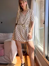 Vestido corto color beige con lunares negros, escote en V, mangas cortas y cinturón ancho color beige.