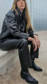 Camisa negra de cuero ovino italiano, con mangas largas, hombros caídos y calce oversize. Tiene cierre frontal con broches metálicos.