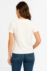 Remera blanca de algodón con cuello redondo, manga corta y apliques de flores bordadas.