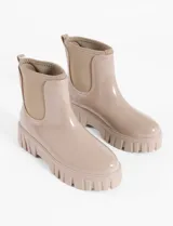 Bota de lluvia impermeable color beige, con suela gruesa y diseño moderno.