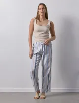 Pantalón de lino estampado a rayas verticales en tonos celeste, beige y blanco. Tiene pretina ancha elastizada con lazo ajustable.