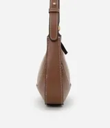 Bolso baguette pequeño color marrón con costuras en contraste color blanco. Tiene correa de hombro ajustable y cierre de cremallera.
