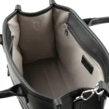Cartera negra de cuero sintético con textura graneada, doble asa corta y correa larga regulable extraíble. Tiene cierre superior, bolsillo interno con cierre y dos bolsillos abiertos.