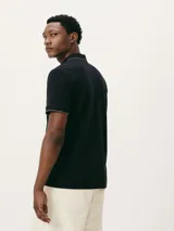 Camisa polo color rosa claro con cuello clásico, tapeta de dos botones y bordado de logo en el pecho. Presenta ribete azul marino en cuello y mangas. Corte clásico.