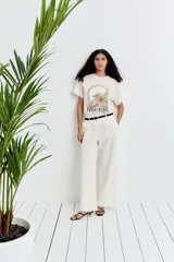 Pantalón de lino color blanco, de corte ancho y tiro alto, con bolsillos laterales y cierre frontal con botón.