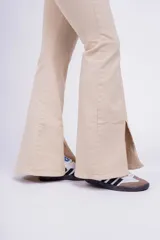 Pantalón Oxford color beige con corte ajustado en la parte superior y acampanado con aberturas en el ruedo.