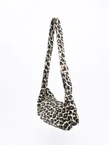 Cartera bandolera con estampado animal print en tonos grises y negros. Tiene correa corta ajustable con hebilla dorada y cierre superior con cremallera dorada.