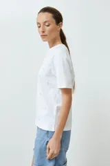 Remera blanca de algodón con cuello redondo y apliques circulares plateados.