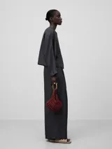 Bolso de mano tipo clutch, color verde, con abalorios tejidos en tricot. Tiene un compartimento con cierre de cremallera y cierre magnético. El asa de mano es metálica con el logo grabado.