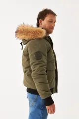 Campera Wrangler de hombre, modelo Teddy, color verde militar con capucha desmontable con borde de piel sintética, cierre frontal con cremallera y botones a presión, bolsillos laterales con solapa y puños y cintura acanalados en negro.