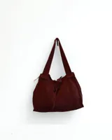 Cartera marrón de cuero con flecos y doble asa circular metálica.