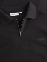 Chomba Calvin Klein negra de algodón, con cuello polo y media cremallera. Tiene mangas cortas y parche de goma con el logo de la marca en el pecho.