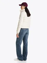 Campera Tommy Hilfiger color blanco, acolchada con plumón, de corte regular. Tiene cuello chimenea, capucha plegable, cierre de cremallera, dos bolsillos laterales con cremallera, puños elásticos con botones a presión y parche con el logo de la marca en la manga.